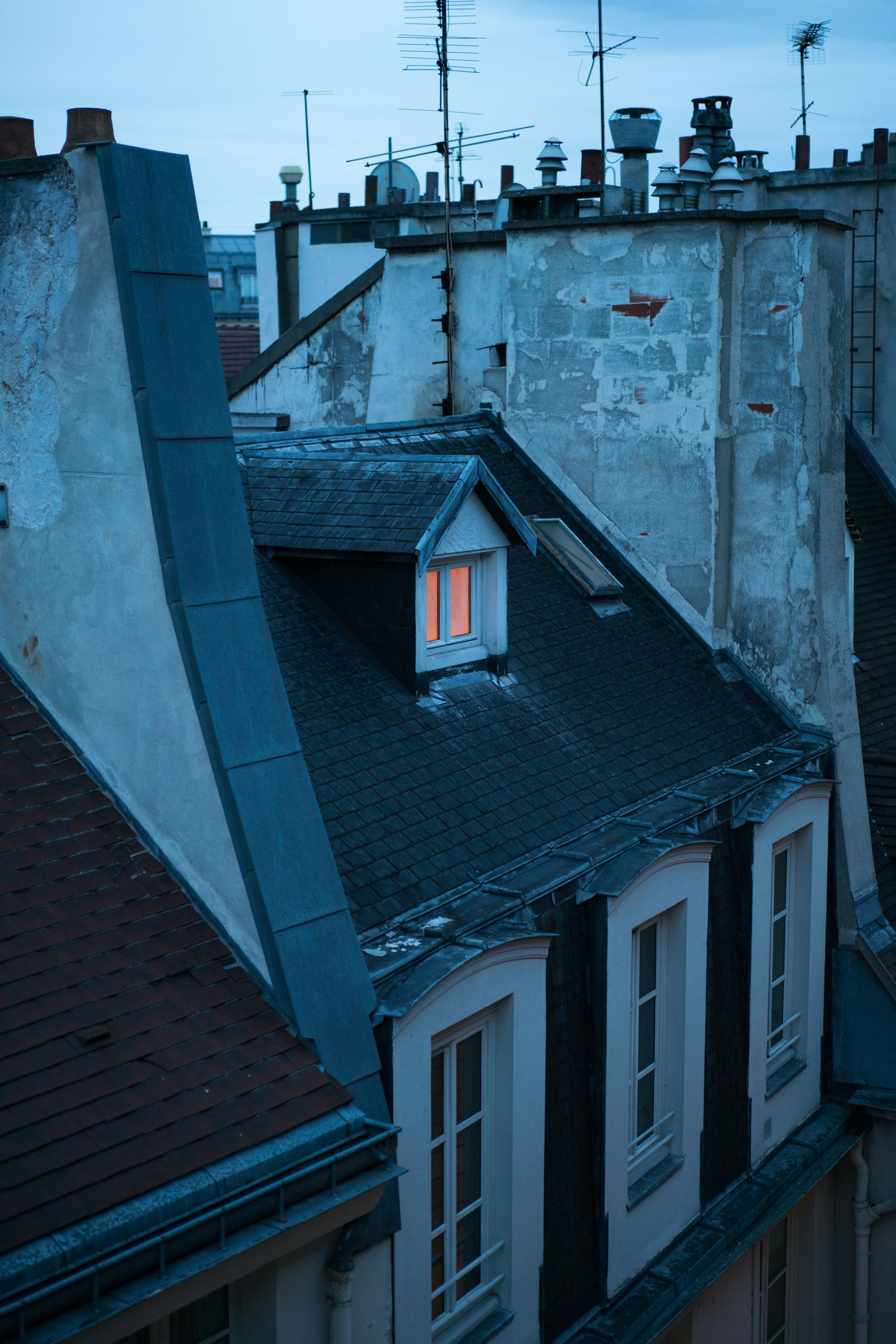 Old fashioned rooftop and windows of shabby building in European city on quiet dusky evening