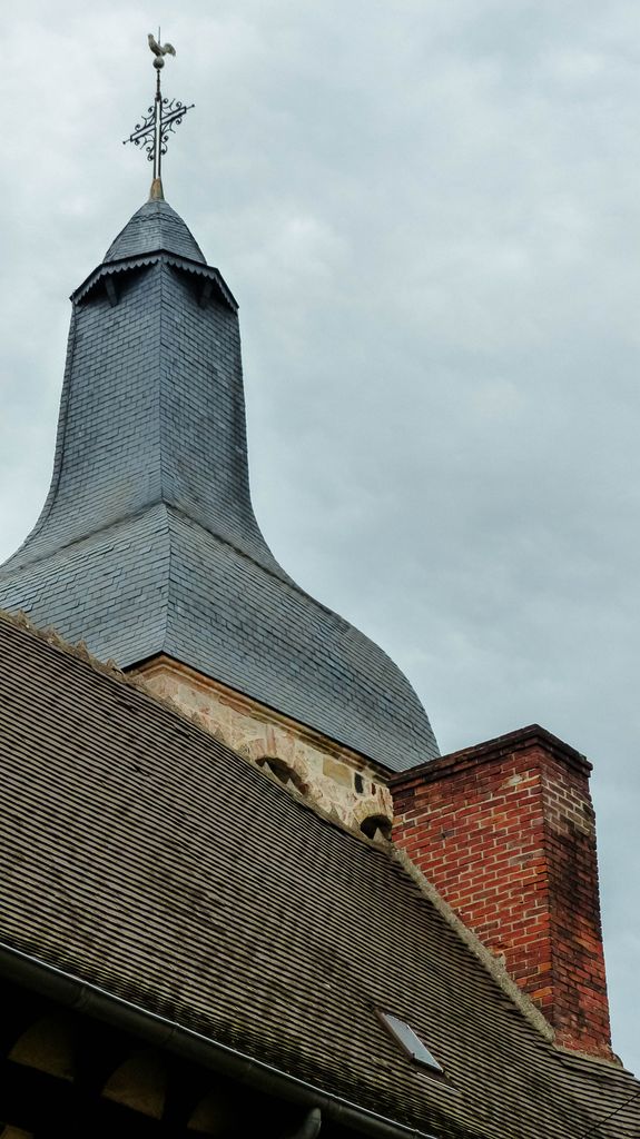 Vertical shot of a church tower in Montluçon, France, under overcast skies.